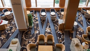 Een moderne hotellobby met een kroonluchter in het midden, zitgedeeltes en grote ramen met uitzicht op de omgeving.