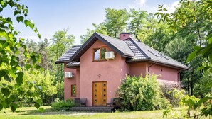 A pink house with a tiled roof, surrounded by lush greenery. - Roso 3 bedroom modern country house (gmina Chynów)