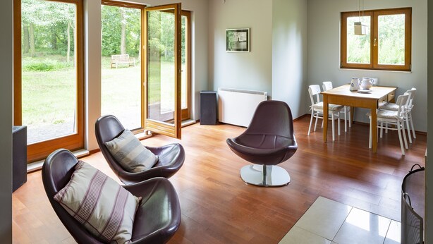 A modern living room with a large window, a dining area with a table and chairs, and a seating area with two chairs. - Roso 3 bedroom modern country house (gmina Chynów)