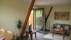 Ein Wohnzimmer mit einem Holztisch, einer Couch, einem Fernseher und einem großen Fenster.