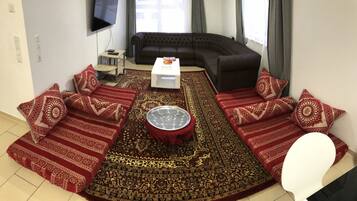 A living room with a sectional sofa, a coffee table, and a patterned rug.