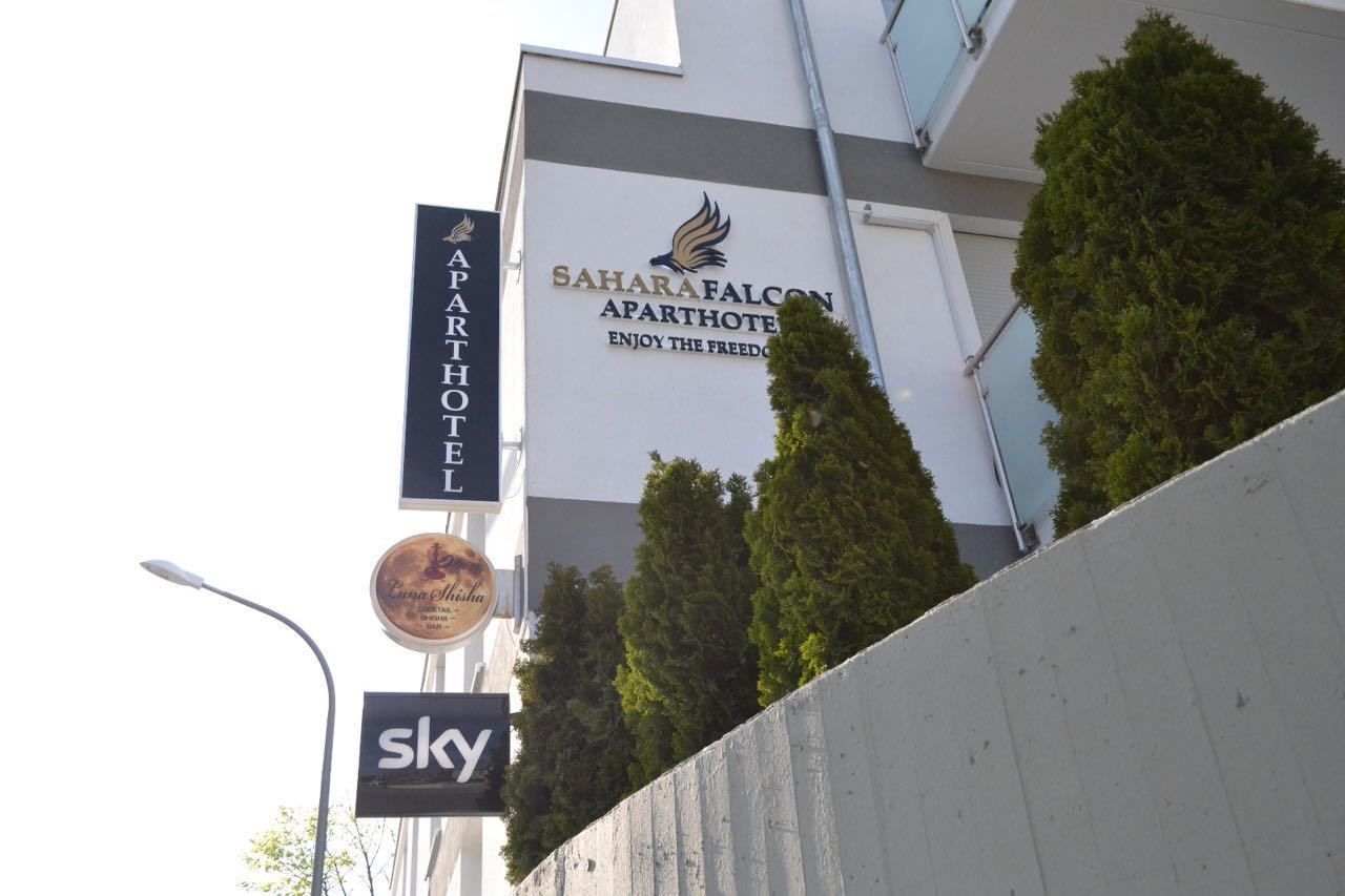 Un immeuble portant une enseigne indiquant « SaharaFalcon Apartments », avec un logo et le texte : « Profitez de la liberté. »