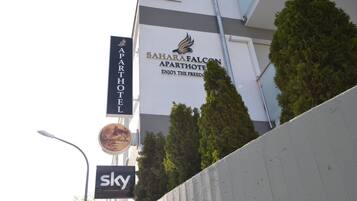 Un immeuble portant une enseigne indiquant « SaharaFalcon Apartments », avec un logo et le texte : « Profitez de la liberté. »