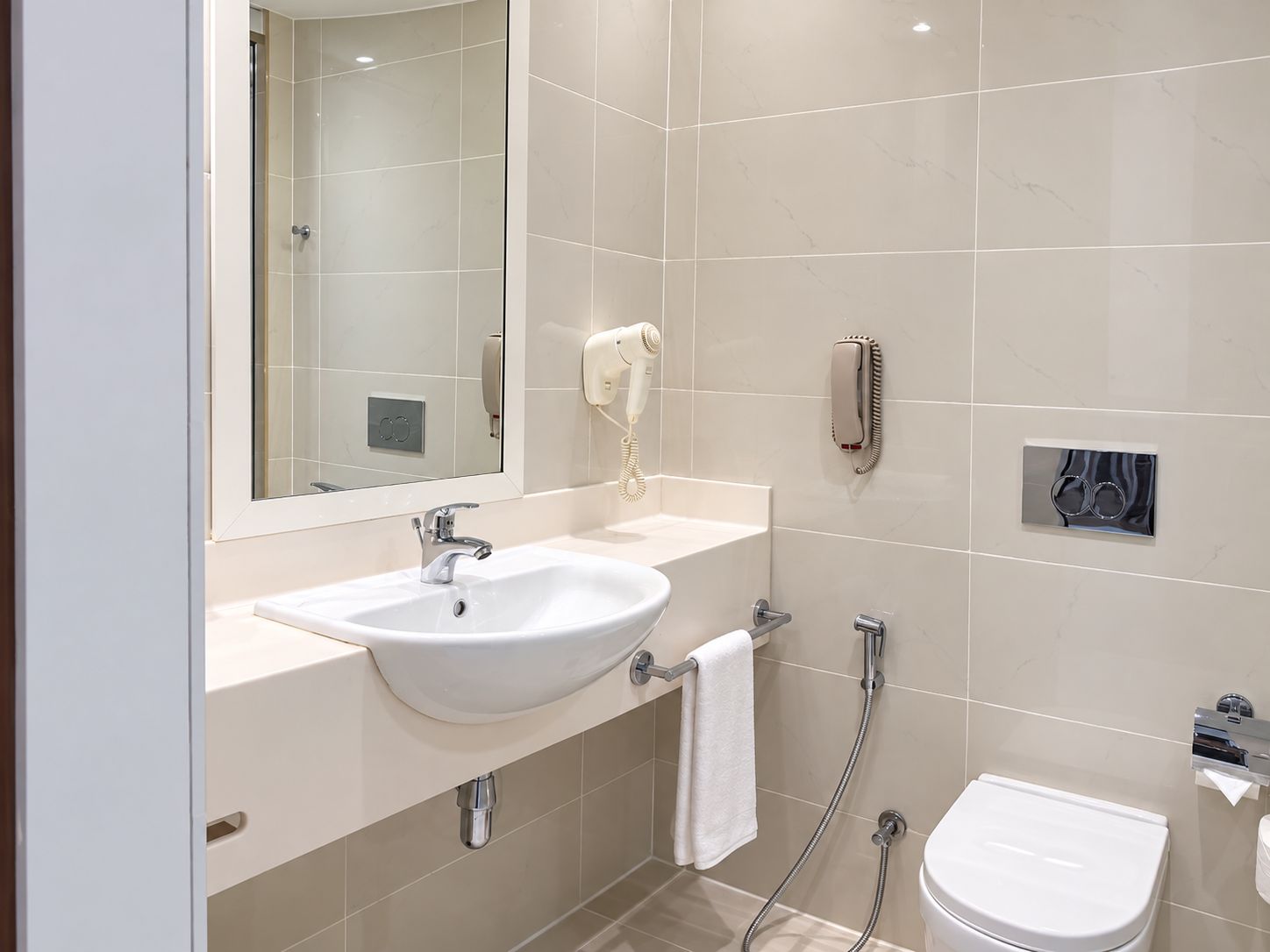 A modern bathroom with a sink, mirror, toilet, and towel rack.
