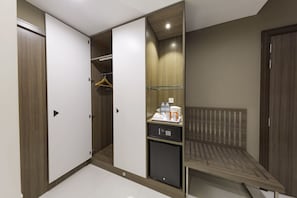 A hotel room with a wardrobe, a small refrigerator, a bed, and a bedside table. - Nooa Hotel Ras Al Khaimah (Ras Al Khaimah)