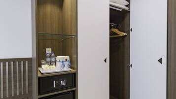 Quarto de hotel com guarda-roupa, mini-frigorífico e um banco.