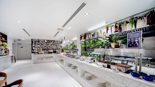 A modern buffet setup with a variety of food items and a wall with food-related words. - Citymax Hotel Ras Al Khaimah (Ras Al Khaimah)
