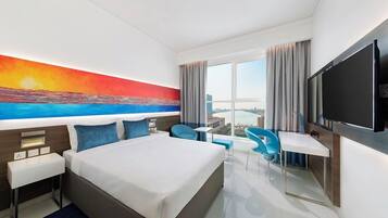 A hotel room with a large bed, a desk, a chair, and a TV.