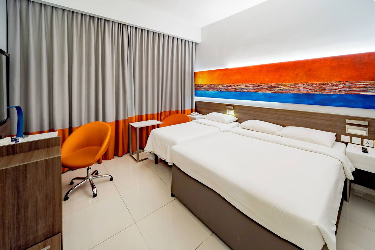 A hotel room with a large bed, a desk with a chair, a TV, and a painting on the wall.
