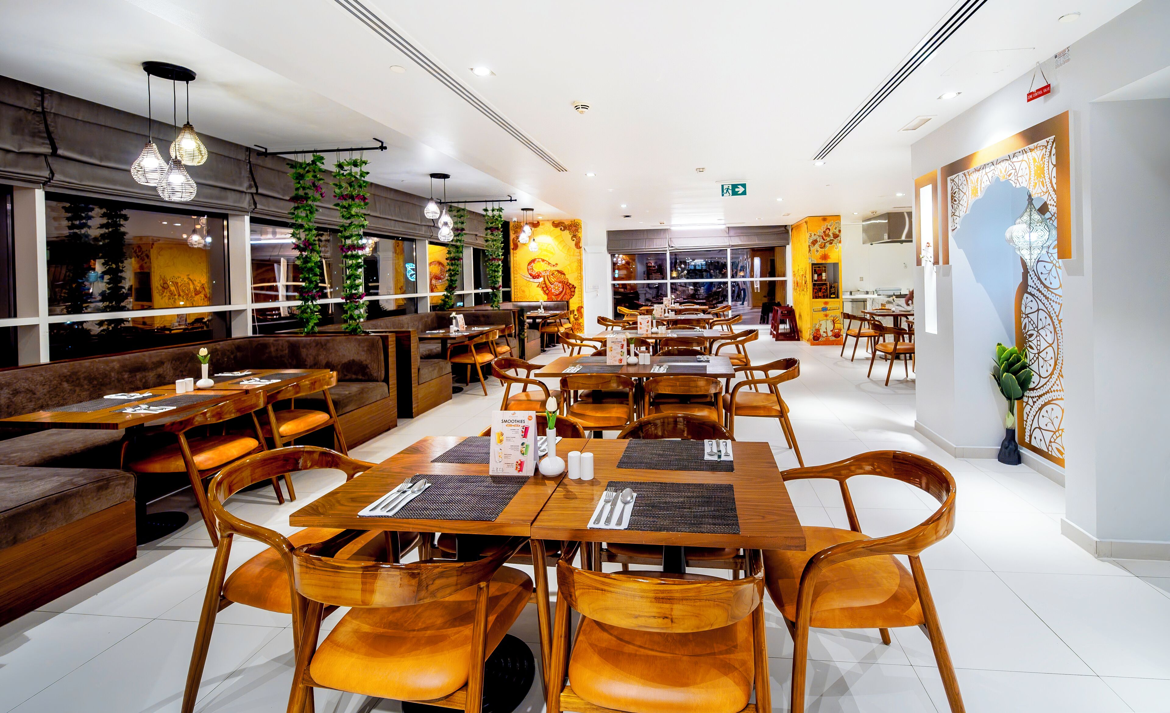 A restaurant with wooden tables and chairs, a bar area, and a large mural on the wall.