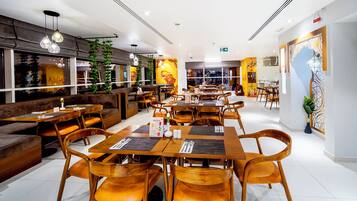 A restaurant with wooden tables and chairs, a bar area, and a large mural on the wall.