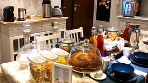 A breakfast buffet with various food items and beverages, a coffee maker, and a kettle on a counter. - Francis B&B Superior (Trieste)