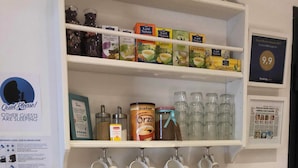 A coffee station with various brewing equipment and coffee pods, a sign encouraging guests to enjoy their stay, and a framed certificate on the wall. - Francis B&B Superior (Trieste)