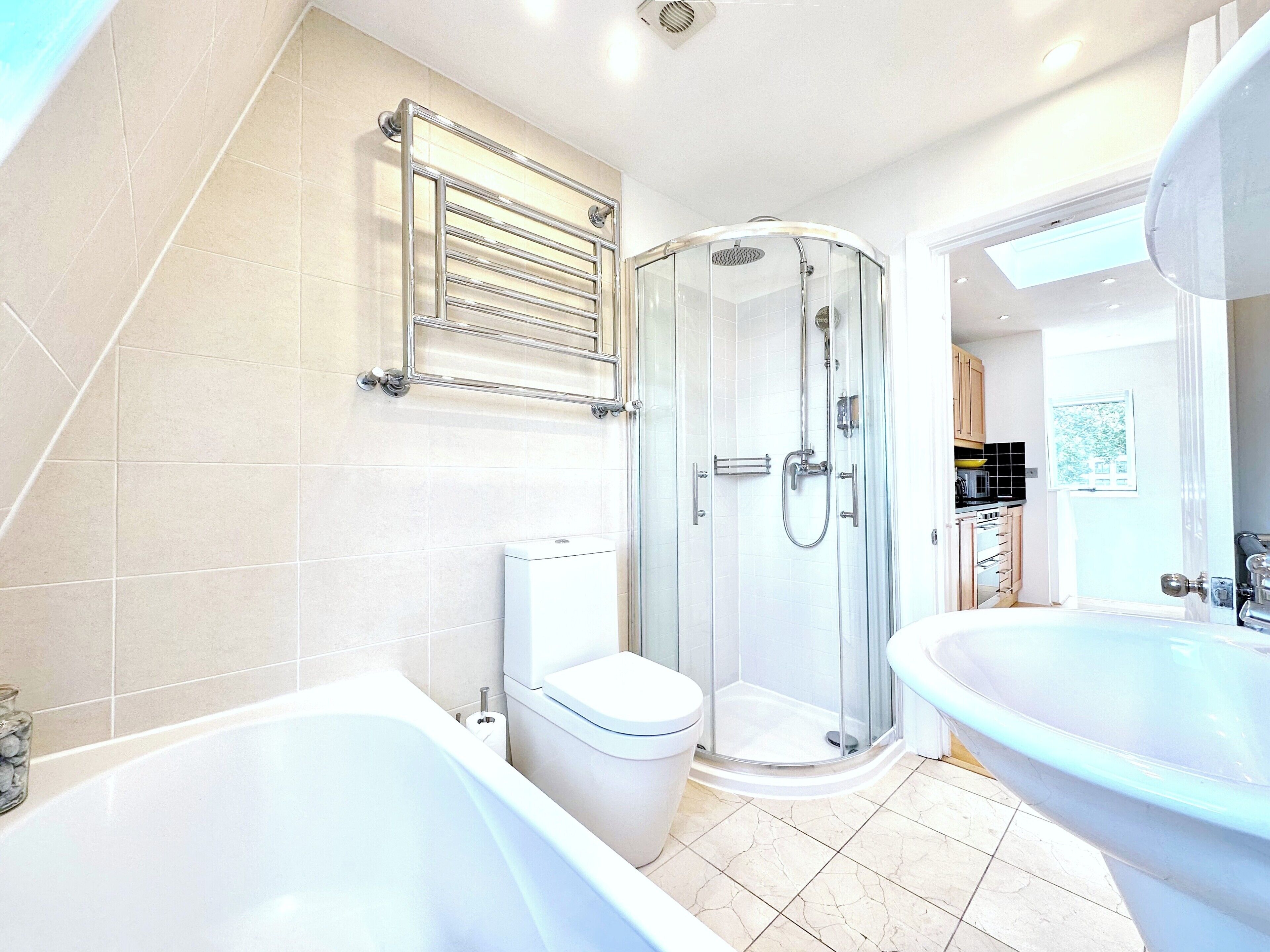 A modern bathroom with a bathtub, toilet, shower, and sink.