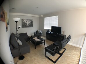 A living room with a sofa, coffee table, and TV stand.