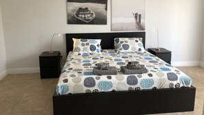A bedroom with a large bed, two nightstands, and two wall-mounted lamps. - Private Home by Ideal Experience VR (Fort Lauderdale)