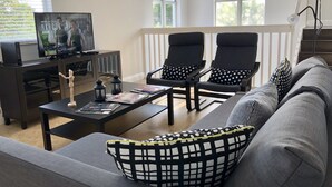 A living room with a sofa, two armchairs, a coffee table, a TV on a cabinet, and a floor lamp. - Private Home by Ideal Experience VR (Fort Lauderdale)