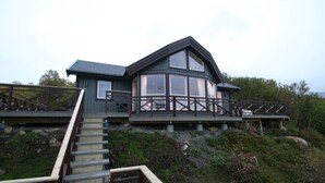 A two-story house with a balcony and a wooden staircase leading to the entrance.