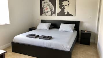 A modern bedroom with a large bed, two bedside tables, and two wall-mounted artworks.