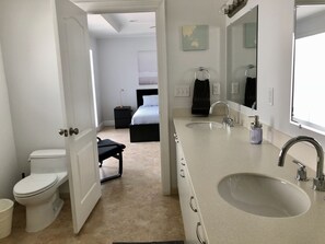 A modern bathroom with a double sink, a toilet, and a bed in the adjacent room. - Luxury Home by Ideal Experience VR (Fort Lauderdale)