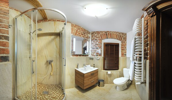 A bathroom with a glass shower enclosure, a wooden vanity, a toilet, and a radiator.