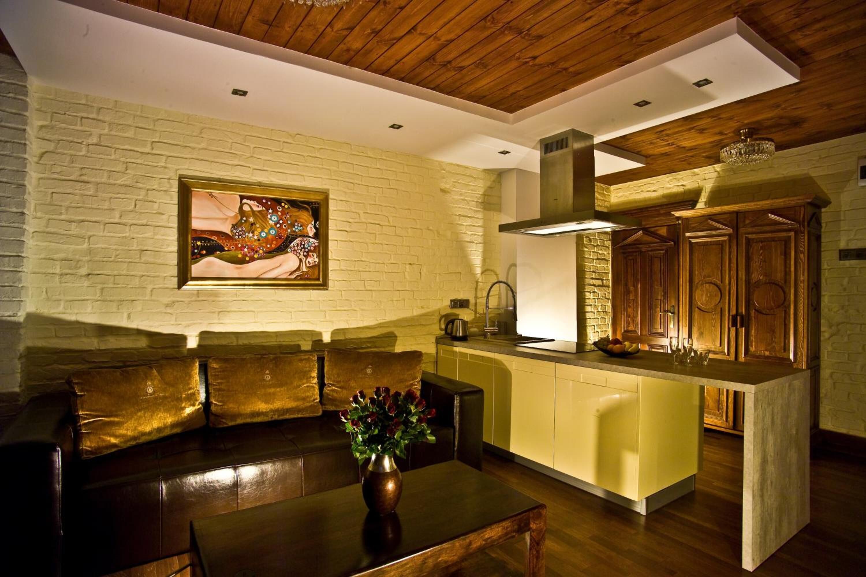 A modern kitchen with a wooden ceiling, a built-in island, and a brick wall.