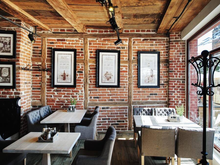Un restaurante con paredes de ladrillo, menús enmarcados y mesas y bancos de madera.
