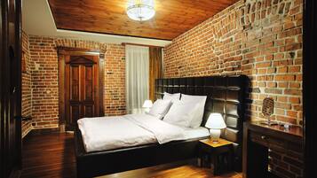 Ein Zimmer mit Backsteinwand, Holzboden und einem Bett mit weißen Leinentüchern.