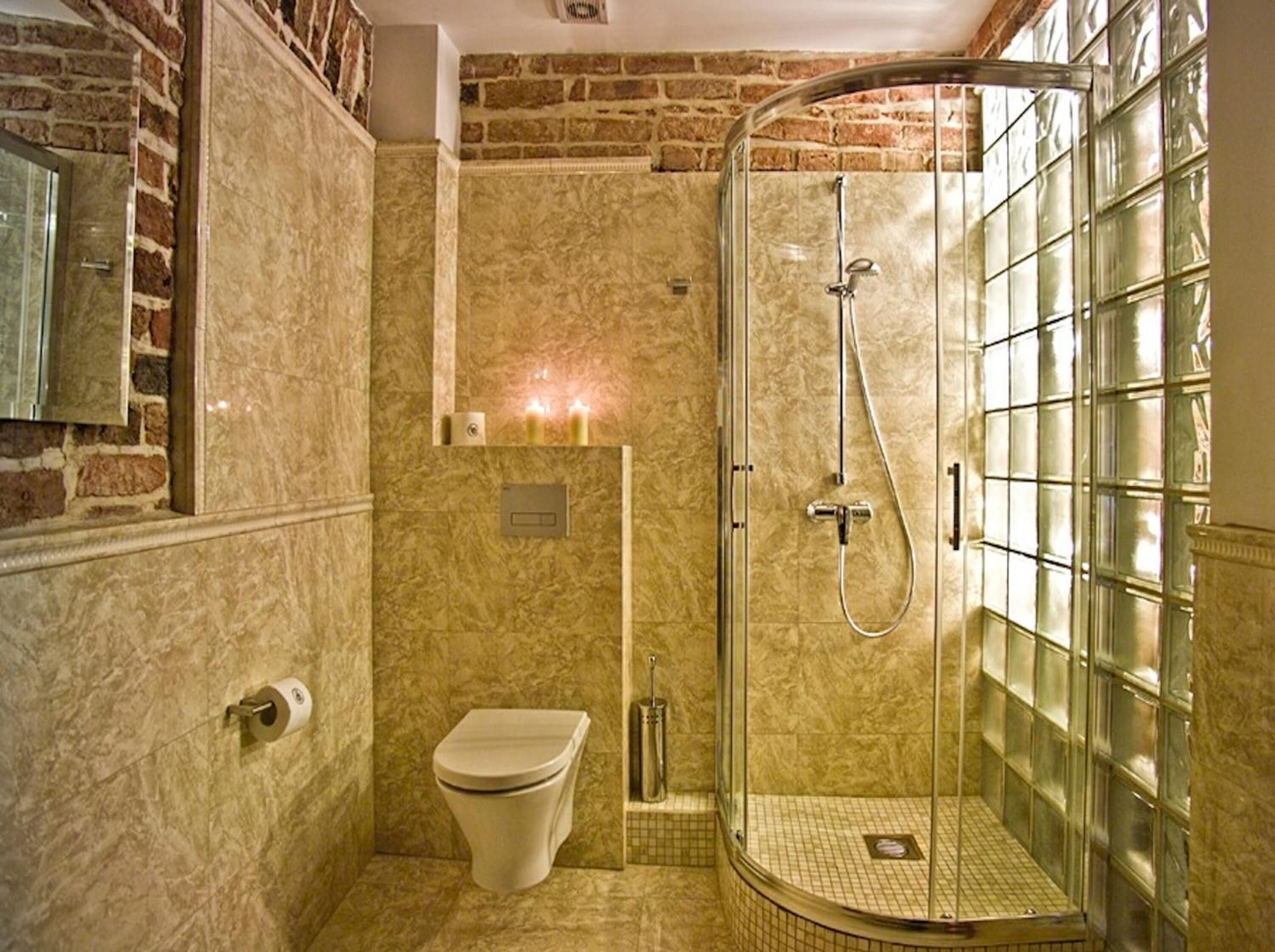 A bathroom with a glass-enclosed shower, a toilet, and a marble wall.