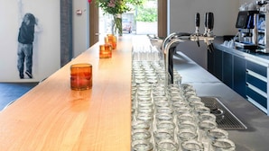 A bar area with a long wooden counter, multiple glasses, and a coffee machine. - SET Hotel.Residence by Teufelhof Basel (Basel)