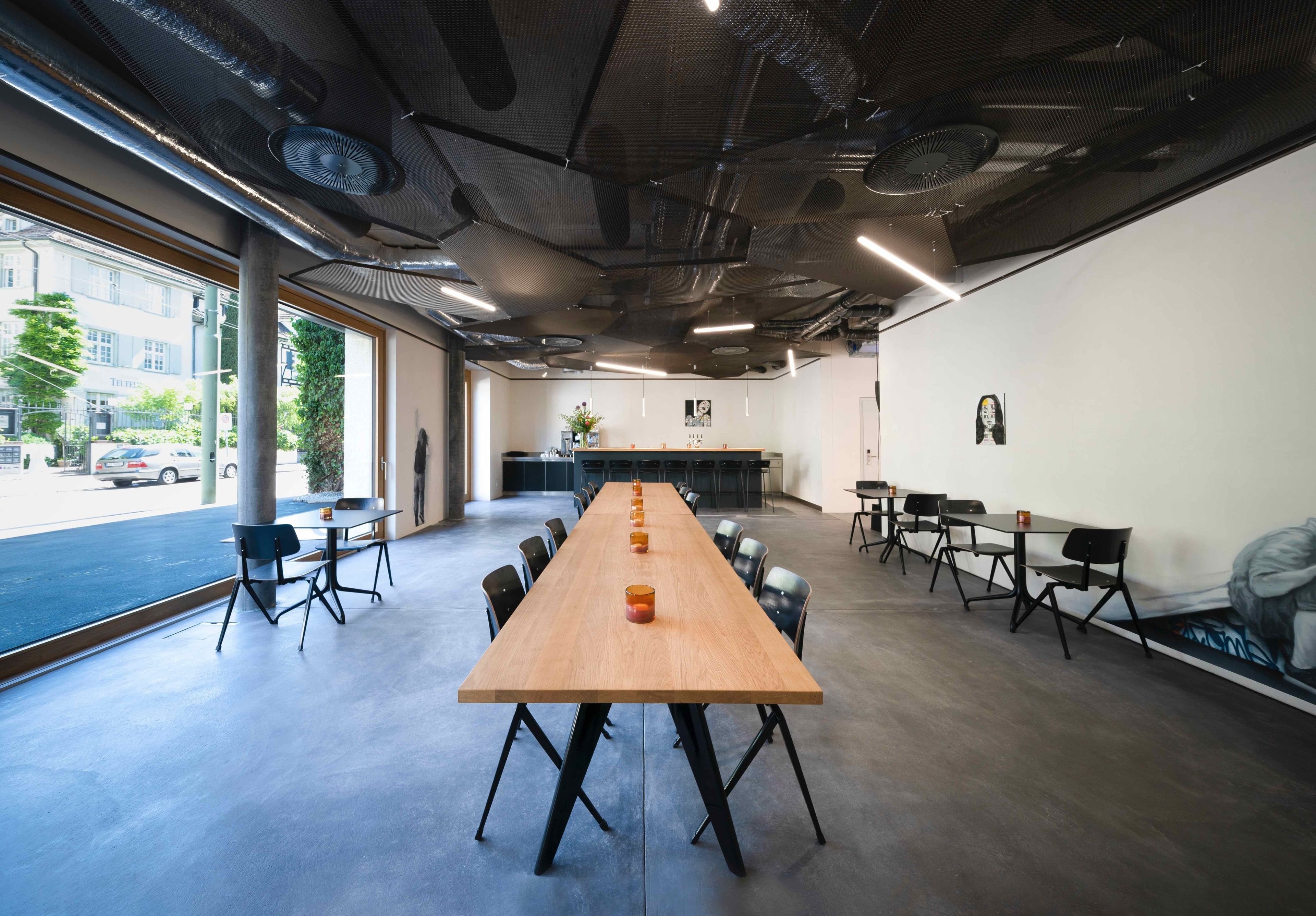 Une salle de conférence avec une longue table en bois, des chaises noires et un tableau blanc à l’avant.