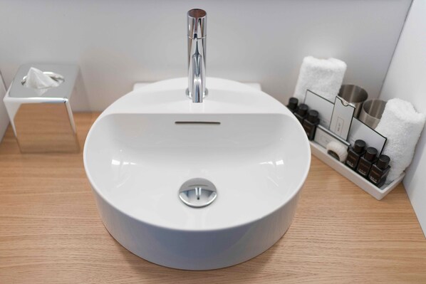 Un baño moderno con un lavamanos blanco, un espejo y un perchero para toallas.