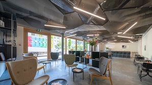 A modern interior with seating areas, a kitchen, and large windows. - SET Hotel.Residence by Teufelhof Basel (Basel)