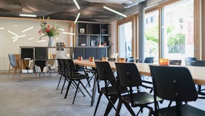 A modern meeting room with a long table, black chairs, and a vase of flowers. - SET Hotel.Residence by Teufelhof Basel (Basel)