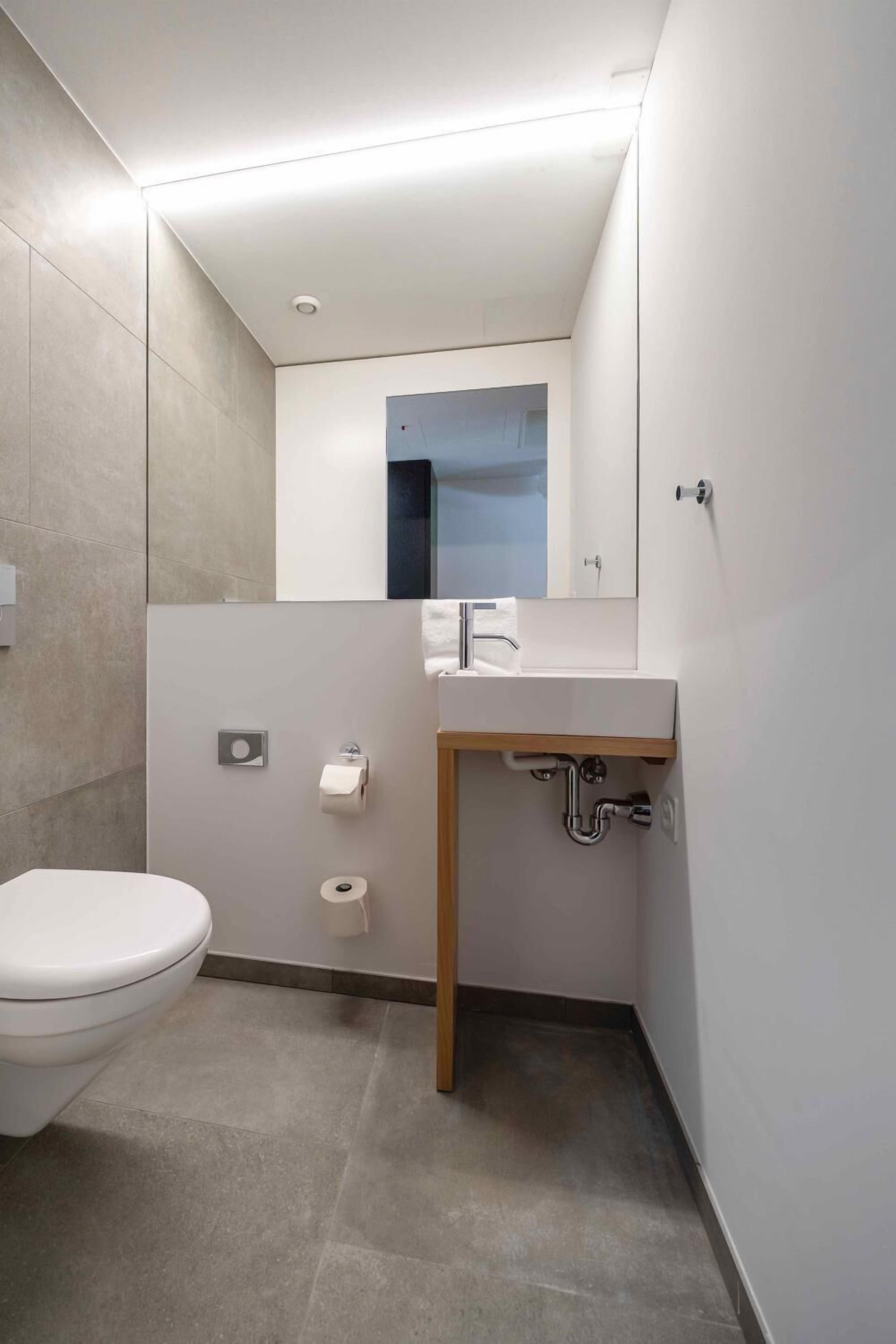 Une salle de bain moderne avec des toilettes, un lavabo et un miroir.
