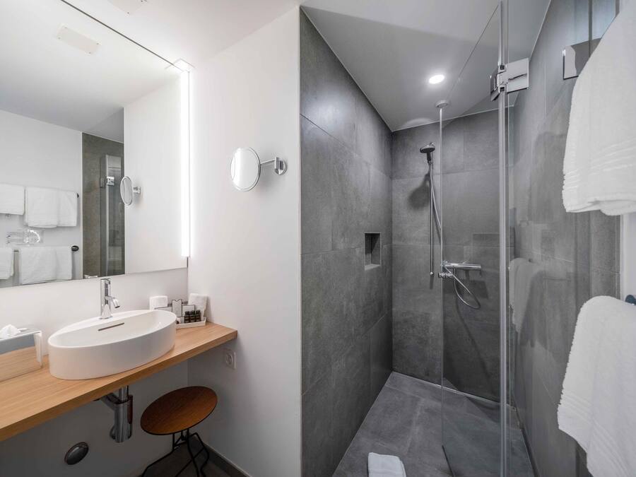 Ein modernes Badezimmer mit einem großen Spiegel, einem Waschbecken und einer Duschkabine.