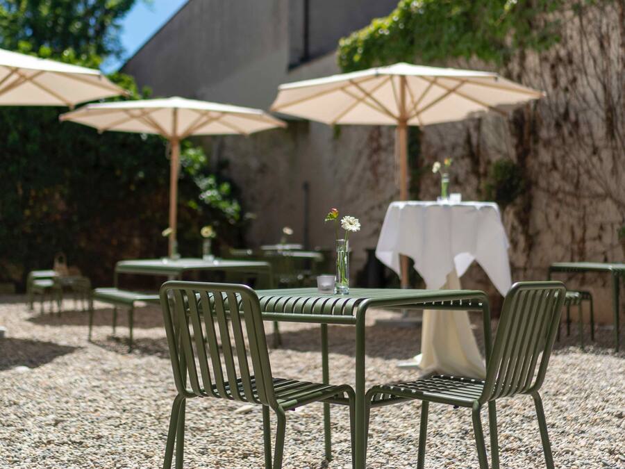 An outdoor patio with tables and chairs, umbrellas, and a building in the background.