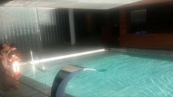 An indoor swimming pool with a clear water surface, a curved edge, and a tiled floor.