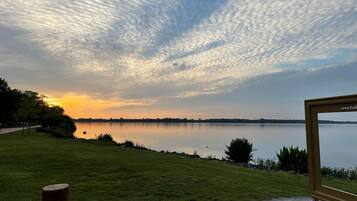 Una vista tranquila del lago, con un poste de madera y un cuadro enmarcado al frente.