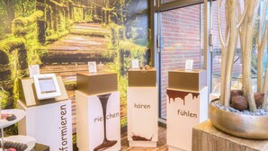 A display area with informational stands and a large mural in the background. - Das Schokoladenhotel (Westerstede)