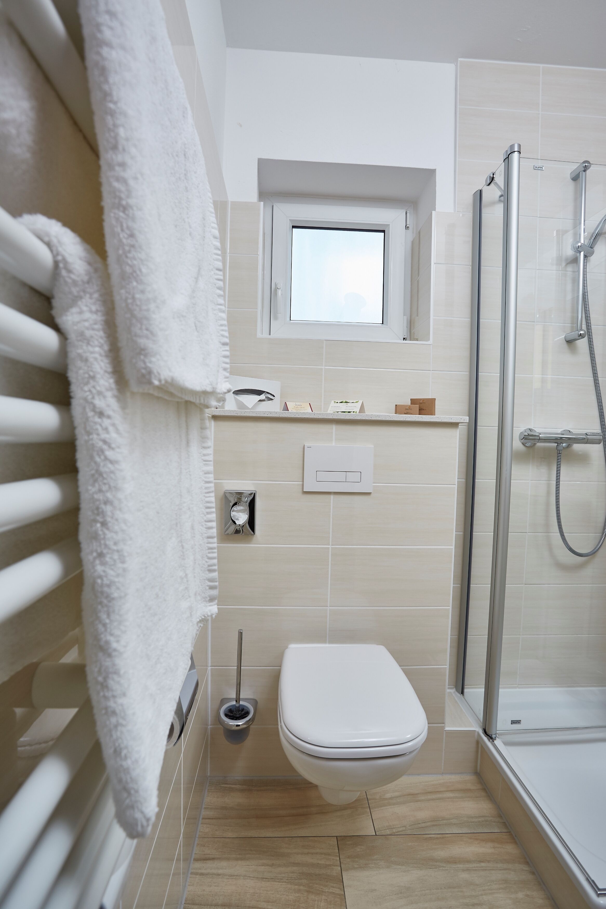 A modern bathroom with a glass-enclosed shower, a toilet, and a towel rack.