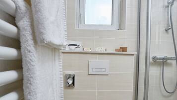 Et moderne badeværelse med bruseniche, toilet og håndklædetørrestativ.