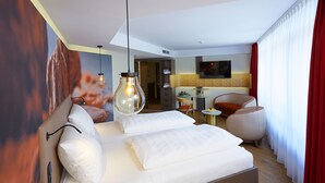 A modern hotel room with a large bed, a desk, a chair, and a television. - Das Schokoladenhotel (Westerstede)