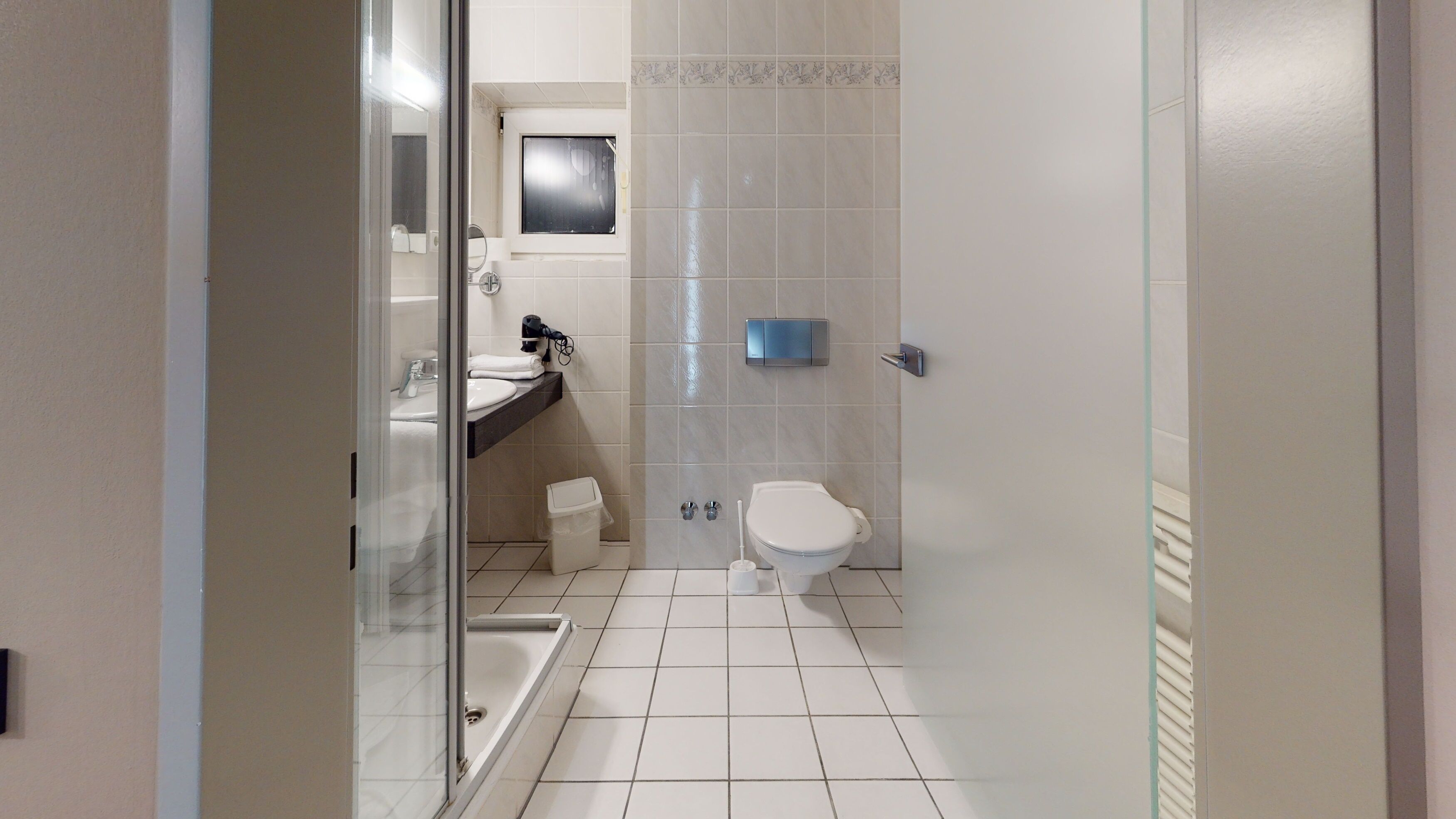 A bathroom with a toilet, sink, and shower area.