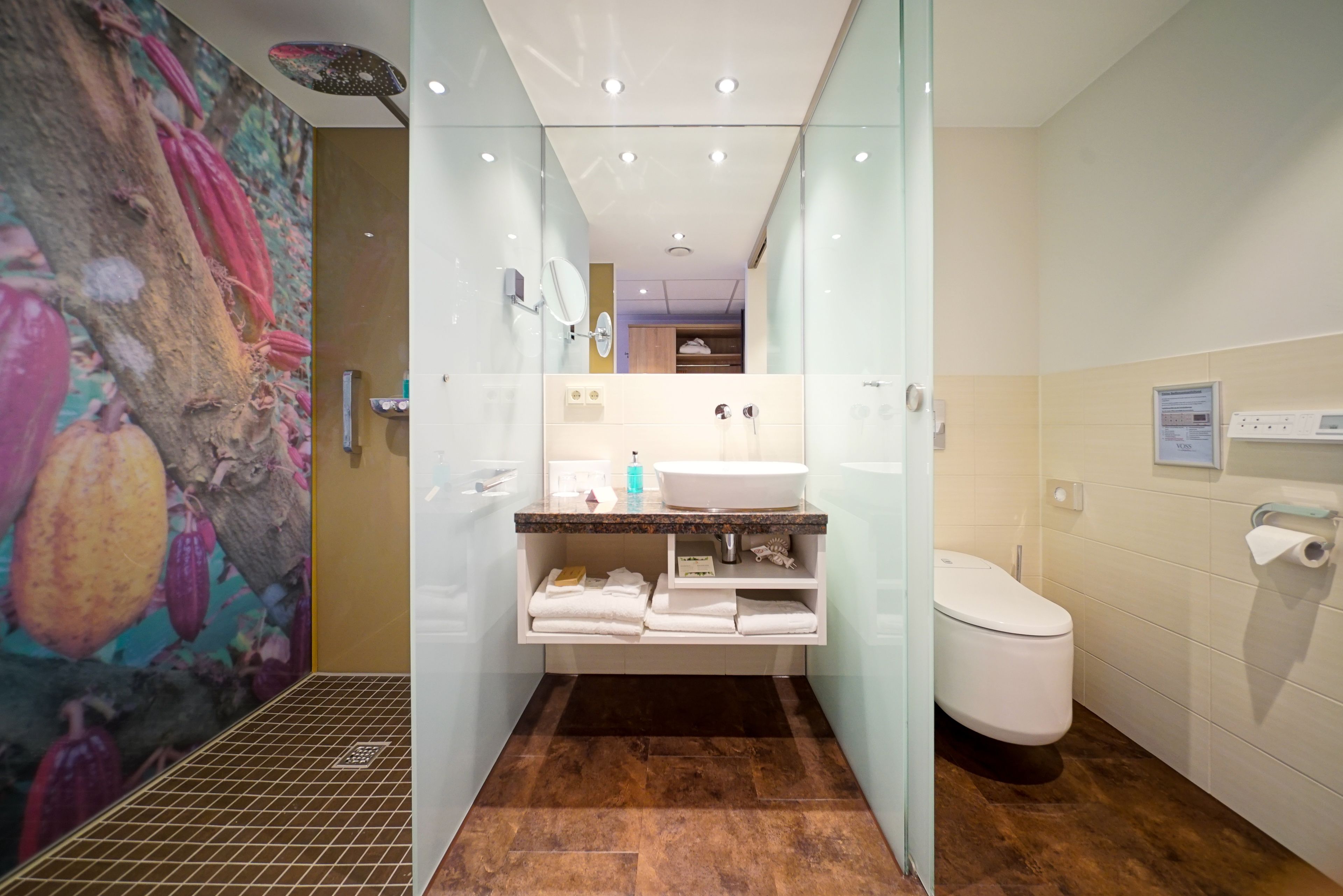 A modern bathroom with a glass shower enclosure, a white sink, and a toilet.