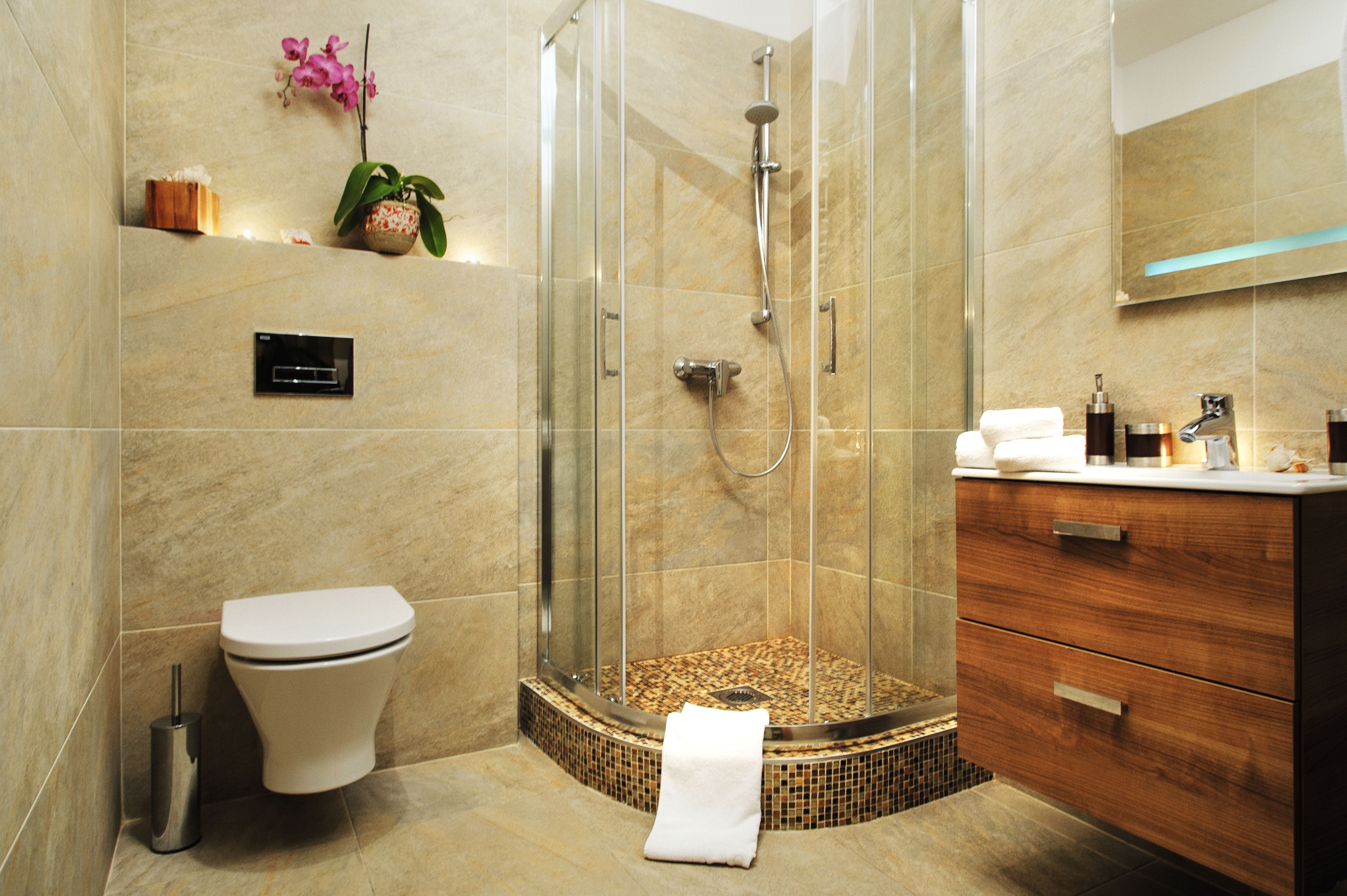Un baño moderno con cabina de ducha de vidrio, inodoro y tocador de madera.