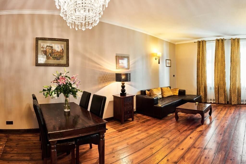 A living room with a wooden dining table, chairs, a sofa, a coffee table, and a chandelier.