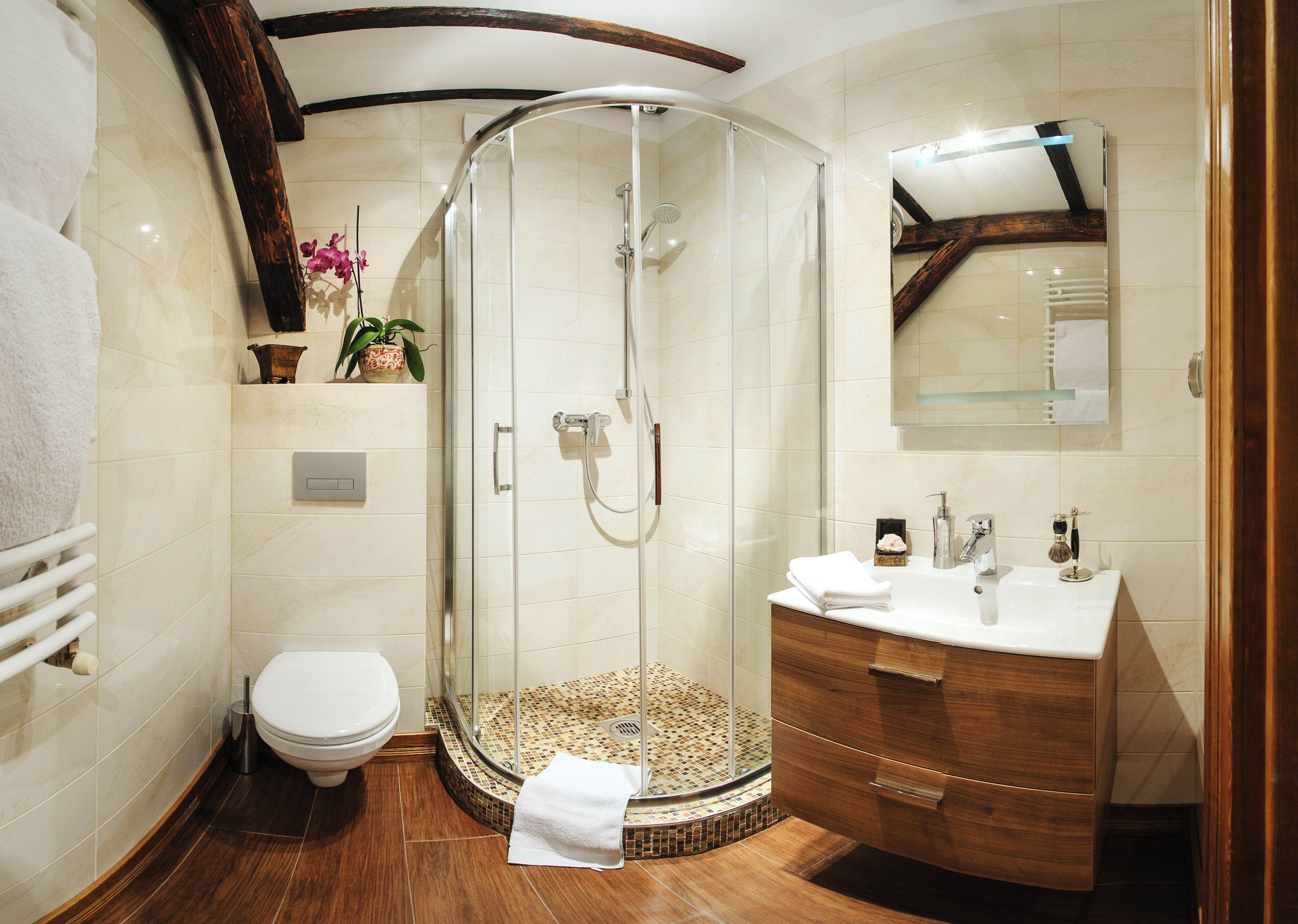 A modern bathroom with a glass-enclosed shower, a white toilet, a wooden vanity with a sink, and a mirror above the vanity.