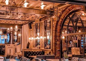 A cozy interior with exposed brick walls, wooden beams, and a variety of hanging light fixtures. - Apartamenty Chleb i Wino Torun (Torun)