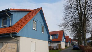 Eine Reihe von blau-weißen Häusern mit roten Dächern, eine gepflasterte Auffahrt und ein geparktes Auto.
